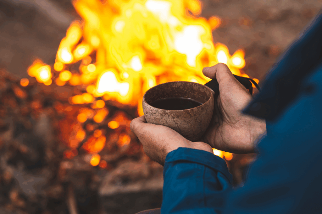 Hands holding a wooden cup by a campfire at Minds and Mountains winter retreat